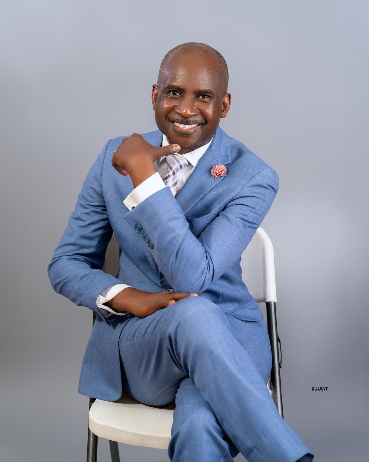 Portrait of Mutiu Babatunde seated in a blue suit